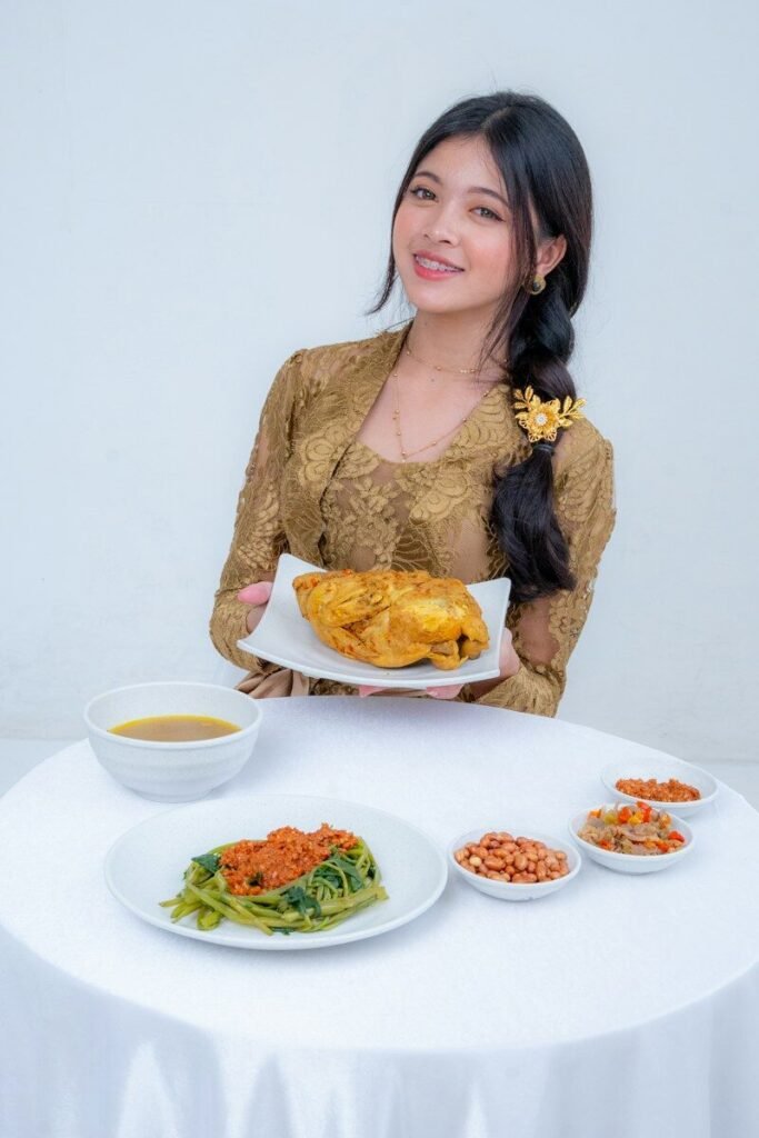 Woman in traditional dress holds roasted chicken with side dishes
